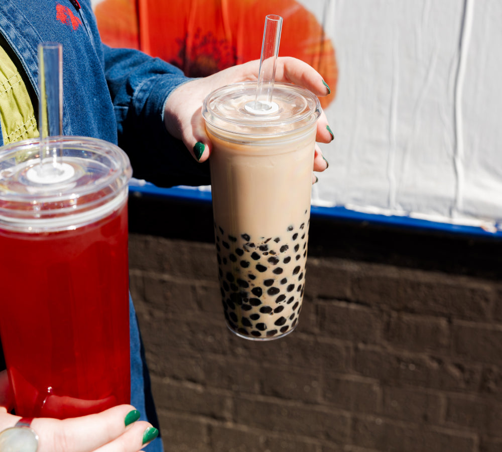 Hands walking and carrying two Cold Cup Original with Brown Sugar Boba and Iced Tea