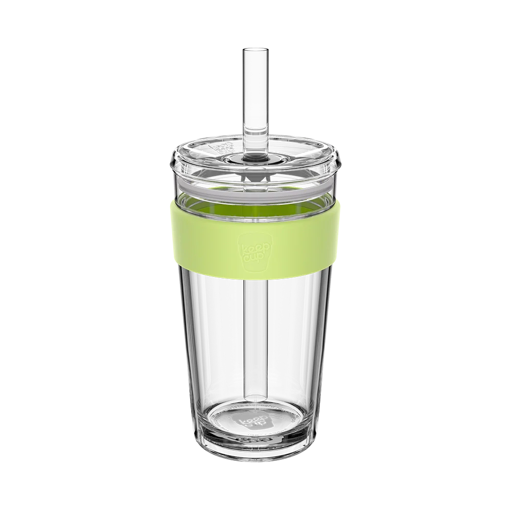 Clear glass tumbler with a green sleeve and straw on a white background