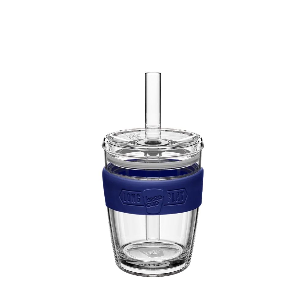 Clear glass tumbler with a blue sleeve and straw on a white background