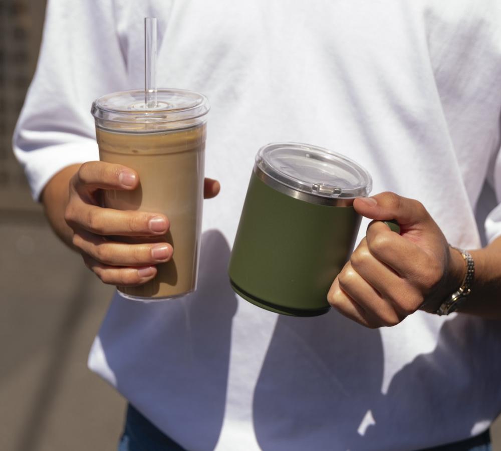 man in white tshirt holding pine camp mug and iced coffee KeepCup