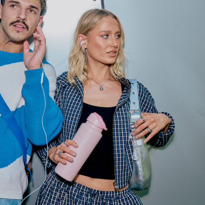 Two people standing next to each other, one holding a pink water bottle.